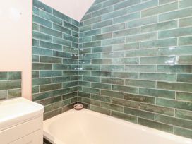 A bathroom with a bathtub and wall tiles at Bohemian Beach Cottage in Bournemouth