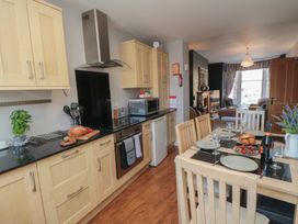 A kitchen with cabinets and dining table at Stanton House - Abbey View, Flat 3