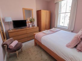 A bedroom with a bed, dresser, and television at Stanton House - Abbey View, Flat 3