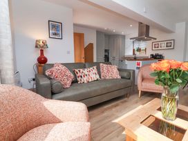 A living room with a sofa, armchairs, and a kitchen area at Butterfly Days in Bideford