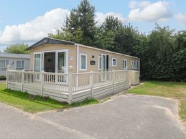 A mobile home with decking and grass at 17 Castle Walk in Great Yarmouth