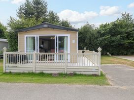 A park home with decking and trees at 17 Castle Walk in Great Yarmouth