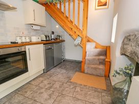A kitchen with cabinets, sink, stove, and staircase at Brondderwen in Blaenau Ffestiniog