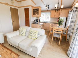 A living room with a couch and dining area at Alpine Lodge Rhyd-y-Foel near Abergele