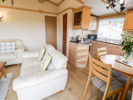 A living room with a sofa and dining area at Alpine Lodge in Rhyd-y-Foel near Abergele