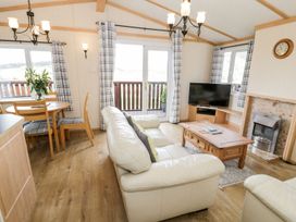 A living room with a sofa and dining table at Alpine Lodge in Rhyd-y-Foel near Abergele