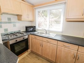 A kitchen with a sink, oven, microwave, and gas stove at Alpine Lodge Rhyd-y-Foel near Abergele