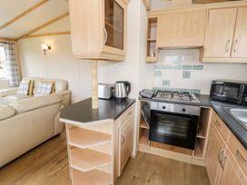 A kitchen with a gas stove and microwave at Alpine Lodge Rhyd-y-Foel near Abergele
