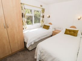 A bedroom with two single beds and a wardrobe at Alpine Lodge in Rhyd-y-Foel near Abergele