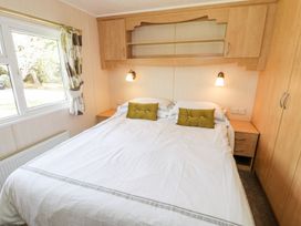 A bedroom with a double bed and storage at Alpine Lodge in Rhyd-y-Foel near Abergele