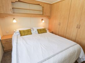 A bedroom with a bed and storage furniture at Alpine Lodge in Rhyd-y-Foel near Abergele