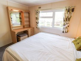 A bedroom with a bed and a desk at Alpine Lodge in Rhyd-y-Foel near Abergele