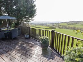 A deck with a table and chairs overlooking fields at Springtime Lodge, Rhyd-y-Foel near Abergele