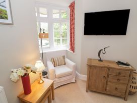 A snug with an armchair and TV mounted on the wall at Raglan Lodge Monmouth