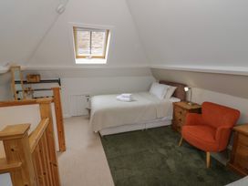 A bedroom with a bed and chair at Raglan Lodge in Monmouth