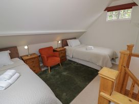 A bedroom with two beds and a chair at Raglan Lodge in Monmouth