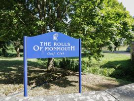 A sign for The Rolls of Monmouth Golf Club with trees and grass nearby
