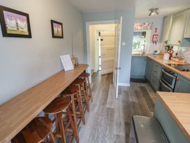 A kitchen with bar stools and cabinets at Hillside Cottage