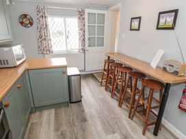 A kitchen with a counter and bar stools at Hillside Cottage