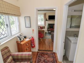 A hallway with an armchair, a phone, and access to a living room at Hillside Cottage