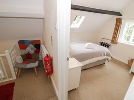 A bedroom with a bed and armchair at Hillside Cottage