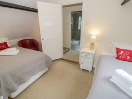 A bedroom with two beds and a door leading to a bathroom at Hillside Cottage