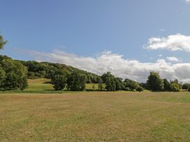 A field with trees and hills under a blue sky at Hillside Cottage in 