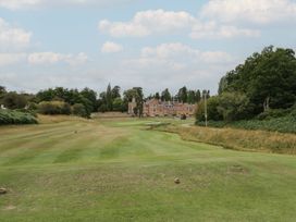 A golf course with a view of a building in the background at Hillside Cottage