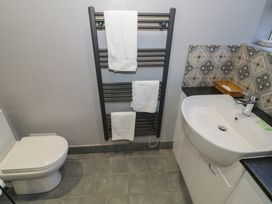 A bathroom with a toilet, towel rack, sink and wall decor at Boxbush Lodge in Monmouth