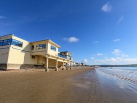 A beach with a building next to the water at 123 On The Sea - The Cubby Weymouth