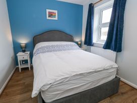 A bedroom featuring a bed, nightstand, lamp and window at 23 The Maltings Weymouth