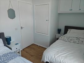 A bedroom with two beds and a nightstand at Dolphin Cottage in Weymouth