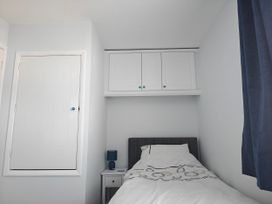 A bedroom with a bed, bedside table, and shelves at Dolphin Cottage in Weymouth