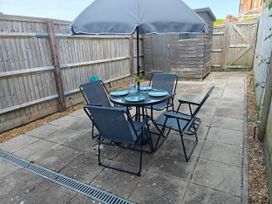 A patio with a table and chairs in the garden at Dolphin Cottage in Weymouth