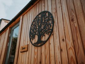A wooden exterior with tree decoration and a sign at Driftwood in Carreglefn near Llanfechell