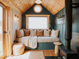 A snug area with cushions and a wood stove at Driftwood in Carreglefn near Llanfechell