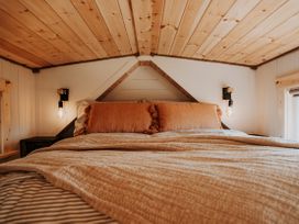 A bedroom with a bed and light fixtures at Driftwood in Carreglefn near Llanfechell
