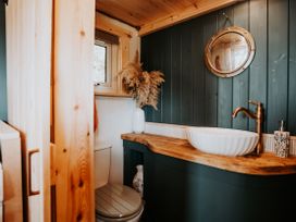 A bathroom with a toilet, wash basin, and mirror at Driftwood in Carreglefn near Llanfechell