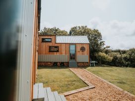 A wooden house with a pathway and grass at Driftwood Carreglefn near Llanfechell