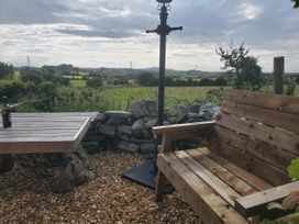 An outdoor area with a wooden table and a bench at Driftwood in Carreglefn near Llanfechell