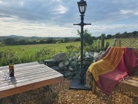 An outdoor seating area with a table and lamp post at Driftwood Carreglefn near Llanfechell
