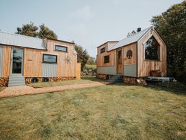 Two tiny houses with wooden exteriors and metal roofs in a garden at Rowan near Llanfechell