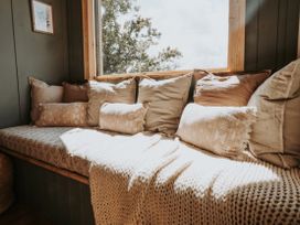 A snug with cushions and a blanket by a window at Rowan in Carreglefn near Llanfechell