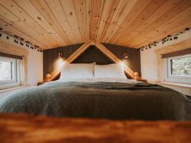 A bedroom with a bed and windows at Rowan in Carreglefn near Llanfechell