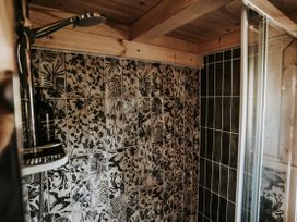 A shower with decorative tiles and a shelf at Rowan in Carreglefn near Llanfechell