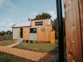 A tiny house with wooden exterior and steps at Rowan in Carreglefn near Llanfechell