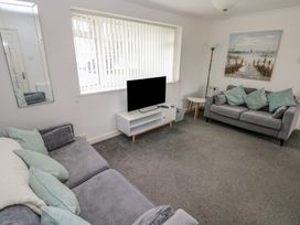 A living room with a sofa and television at Chalet 26 in Scurlage