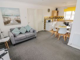A living room with a couch and a kitchen area at Chalet 26 in Scurlage