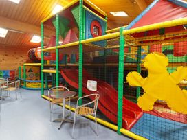 An indoor play area with a climbing structure and tables at Chalet 26 in Scurlage