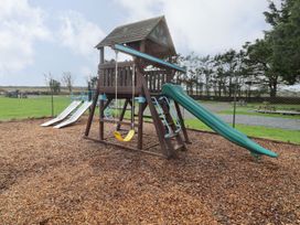 A playground structure with slides and swings at Chalet 26 in Scurlage